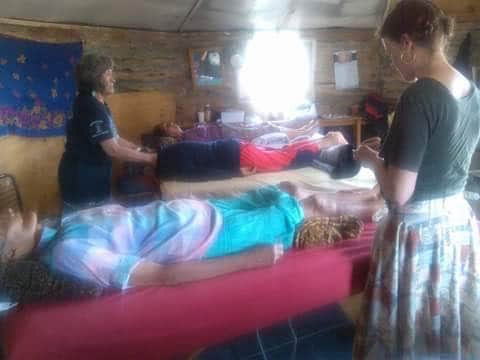 A photo of clinic volunteers doing body work and acupuncture in a cozy hogan, with light streaming in a window in the background.